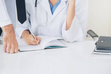 Doktor hastane ofis notlar hastalar raporda başka bir doktor ile konuşma yaparken o ayakta yanında yazıyor.