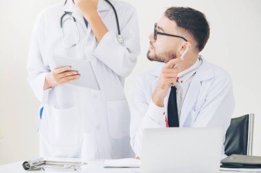 Doktor hastane ofis dizüstü bilgisayar masanın üzerinde başka bir doktor hasta sağlık hakkında tartışma ile çalışma.