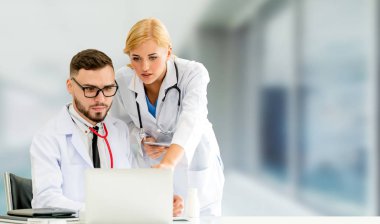 Doktor hastanede başka bir doktor ile bir tartışma yaparken ofiste dizüstü bilgisayarla çalışma. Tıbbi sağlık ve doktor hizmeti.