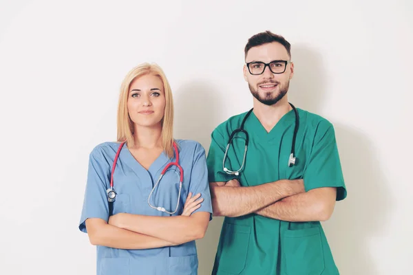 Portrait of confident GP doctor and surgical doctor with arms crossed on white background.