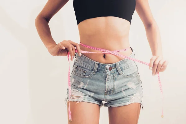 年轻苗条的女人测量她的腰部后 饮食对白色背景的磁带 减肥成功概念 — 图库照片