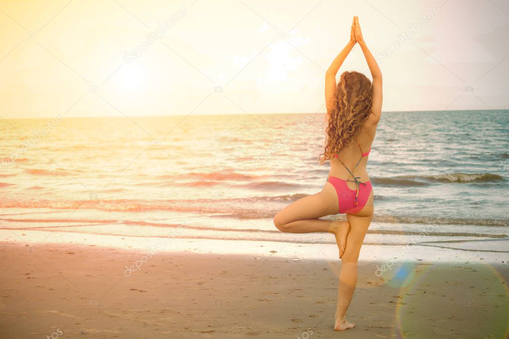 Young woman practicing yoga pose on the beach in summer. Healthy lifestyle and meditation.