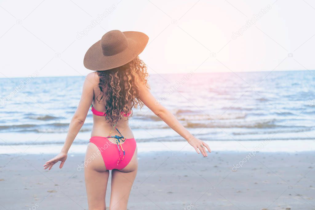 Happy young woman wearing swimsuit having good time at tropical beach in summer for holiday travel vacation.