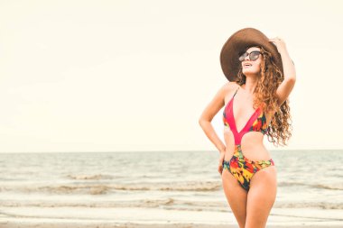 Tatil seyahat etmek tatil için yaz aylarında tropikal plaj keyfi yerinde mayo giyen mutlu genç kadın.