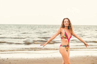 Tatil seyahat etmek tatil için yaz aylarında tropikal plaj keyfi yerinde mayo giyen mutlu genç kadın.