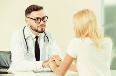 Erkek doktor hastane ofiste bayan hasta hasta ellerini tutarak yatıştırır. Sağlık ve tıbbi hizmet.