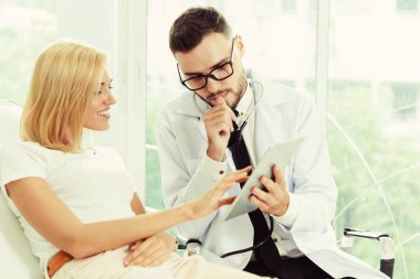 Erkek doktor ve Bayan hasta sağlık veri kaydı için tablet bilgisayar bakıyor. Sağlık ve tıbbi hizmet.