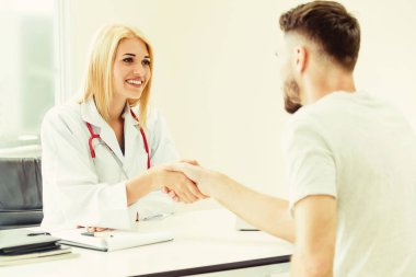 Kadın doktor hastane office odasında erkek hasta ile karşılıklı yapıyor. Sağlık ve Medikal hizmet meslekleri.