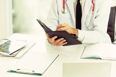 Doktor ofisinde hastanede bir kitap üzerine not yazarken okuma. Tıbbi ve sağlık kavramı.