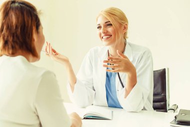 Kadın doktor konuşuyor ve Bayan hasta hastane ofisinde inceleyerek. Sağlık ve tıbbi hizmet.