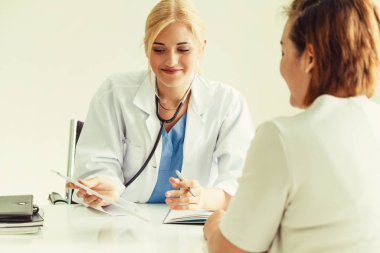 Kadın doktor konuşuyor ve Bayan hasta hastane ofisinde inceleyerek. Sağlık ve tıbbi hizmet.