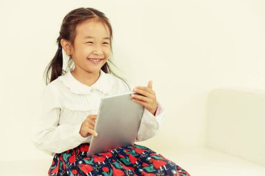 Tablet bilgisayar ile beyaz arka plan üzerinde küçük mutlu çocuk. Çocukluk yaşam tarzı.