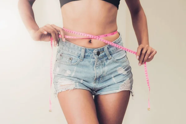 年轻苗条的女人测量她的腰部后 饮食对白色背景的磁带 减肥成功概念 — 图库照片