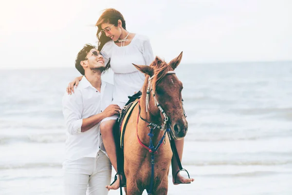 若いカップルがビーチで夏休みに新婚旅行乗馬 — ストック写真