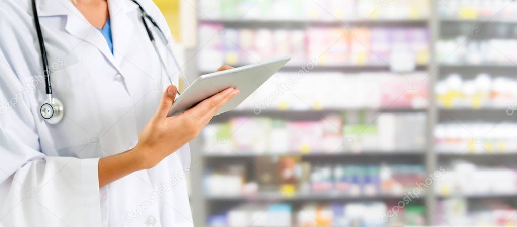 Pharmacist using tablet computer at the pharmacy. Medical healthcare and pharmaceutical staff service.