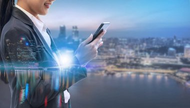 Cep telefonu ile modern şehir binaları arka plan kullanarak genç iş kadını. Gelecekteki telekomünikasyon teknolojisi ve internet şeyler (çok) kavramının.