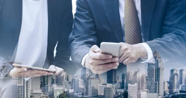 Cep telefonu ile modern şehir binaları arka plan kullanarak genç iş adamları. Gelecekteki telekomünikasyon teknolojisi ve internet şeyler (çok) kavramının.