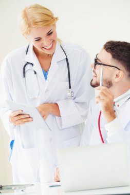 Doktor hastane ofis dizüstü bilgisayar masanın üzerinde başka bir doktor hasta sağlık hakkında tartışma ile çalışma.