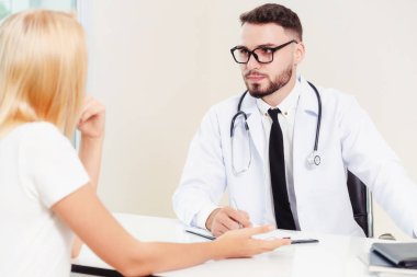 Erkek doktor hastane ofiste bayan hasta konuşuyor. Sağlık ve tıbbi hizmet.