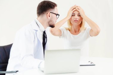 Erkek doktor hastane ofiste bayan hasta masada dizüstü bilgisayarda hastalar sağlık verilere bakarken konuştuğu. Sağlık ve tıbbi hizmet.