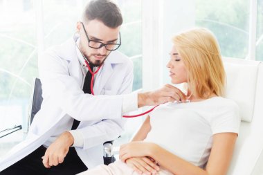 Erkek doktor konuşuyor ve Bayan hasta hastane ofisinde inceleyerek. Sağlık ve tıbbi hizmet.