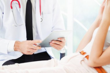 Erkek doktor konuşuyor ve Bayan hasta hastane ofisinde inceleyerek. Sağlık ve tıbbi hizmet.