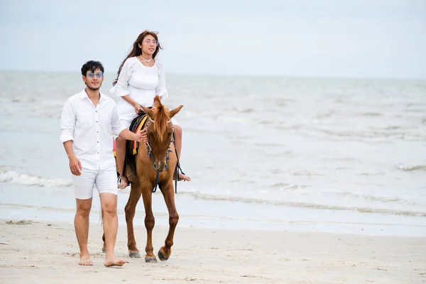 年轻夫妇去蜜月骑马在海滩上的夏天假期 — 图库照片