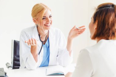 Kadın doktor konuşuyor ve Bayan hasta hastane ofisinde inceleyerek. Sağlık ve tıbbi hizmet.