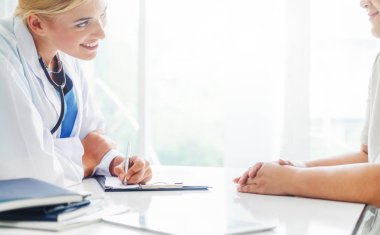 Kadın doktor görüşmeler yazarken bayan hasta için hastanın sağlık kaydının hastane ofiste. Sağlık ve tıbbi hizmet.