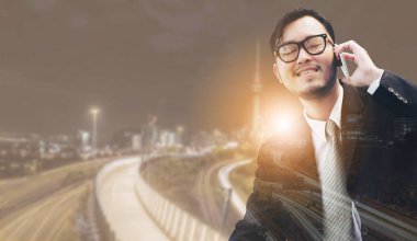 Genç işadamı istimal hareket eden telefon ile modern şehir binaları arka plan.