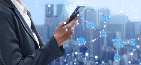 Young businesswoman using mobile phone with modern city buildings background. Future telecommunication technology and internet of things ( IOT ) concept.