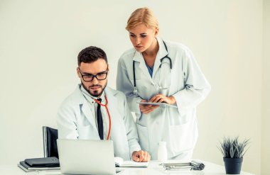 Doktor hastane ofis dizüstü bilgisayar masanın üzerinde başka bir doktor hasta sağlık hakkında tartışma ile çalışma.