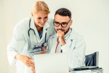 Doktor hastane ofis dizüstü bilgisayar masanın üzerinde başka bir doktor hasta sağlık hakkında tartışma ile çalışma.