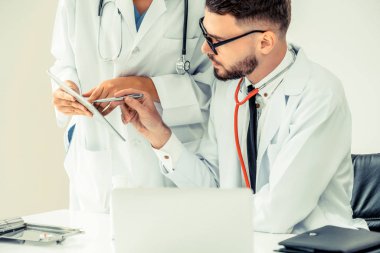 Doktor hastane ofis dizüstü bilgisayar masanın üzerinde başka bir doktor hasta sağlık hakkında tartışma ile çalışma.