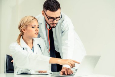 Doktor hastane ofis dizüstü bilgisayar masanın üzerinde başka bir doktor hasta sağlık hakkında tartışma ile çalışma.