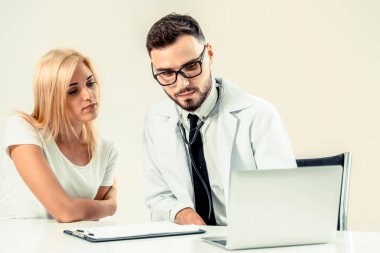Erkek doktor hastane ofiste bayan hasta masada dizüstü bilgisayarda hastalar sağlık verilere bakarken konuştuğu. Sağlık ve tıbbi hizmet.