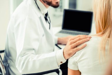 Erkek doktor hastane ofiste bayan hasta masada dizüstü bilgisayarda hastalar sağlık verilere bakarken konuştuğu. Sağlık ve tıbbi hizmet.