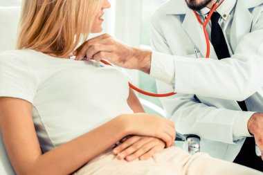 Erkek doktor konuşuyor ve Bayan hasta hastane ofisinde inceleyerek. Sağlık ve tıbbi hizmet.