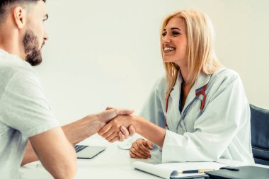 Kadın doktor hastane office odasında erkek hasta ile karşılıklı yapıyor. Sağlık ve Medikal hizmet meslekleri.