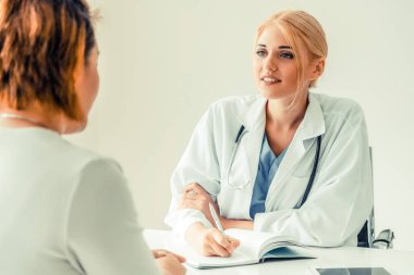 Kadın doktor konuşuyor ve Bayan hasta hastane ofisinde inceleyerek. Sağlık ve tıbbi hizmet.