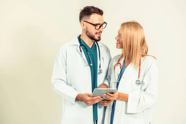 Young surgical doctor holds a tablet computer while discussing with GP doctor on white background. Medical service and healthcare people concept.