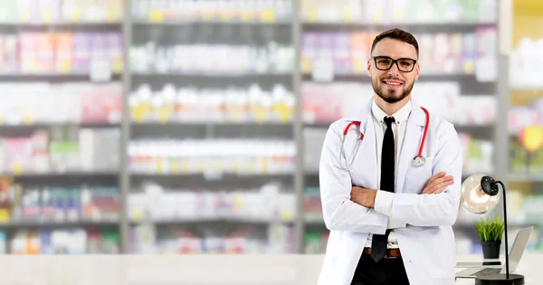 Handsome doctor standing in hospital office and looking at camera. Medical healthcare and doctor staff service.