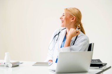 Mutlu başarılı kadın doktor hastane veya Sağlık Enstitüsü hoş ofis masası, tıbbi rapor üzerinde çalışırken düşünüyor. Başarı kavramı.