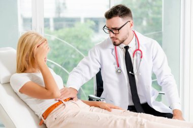 Erkek doktor konuşuyor ve Bayan hasta hastane ofisinde inceleyerek. Sağlık ve tıbbi hizmet.