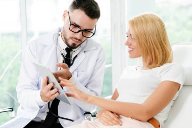 Erkek doktor ve Bayan hasta sağlık veri kaydı için tablet bilgisayar bakıyor. Sağlık ve tıbbi hizmet.