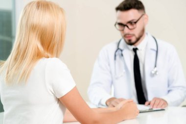 Erkek doktor hastane ofiste bayan hasta konuşuyor. Sağlık ve tıbbi hizmet.
