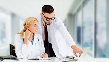 Doktor hastanede başka bir doktor ile bir tartışma yaparken ofiste dizüstü bilgisayarla çalışma. Tıbbi sağlık ve doktor hizmeti.
