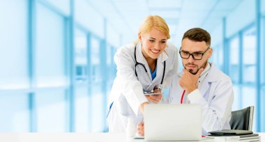 Doktor hastanede başka bir doktor ile bir tartışma yaparken ofiste dizüstü bilgisayarla çalışma. Tıbbi sağlık ve doktor hizmeti.