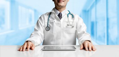 Tablet bilgisayar Hastanesi Office ile masada oturan erkek doktor. Tıbbi sağlık personeli ve doktor hizmeti.