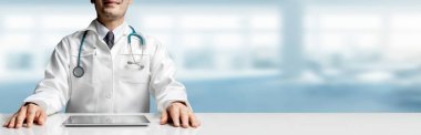 Tablet bilgisayar Hastanesi Office ile masada oturan erkek doktor. Tıbbi sağlık personeli ve doktor hizmeti.